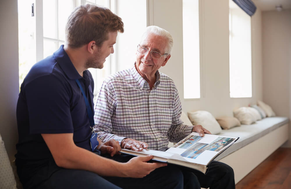 Senior man looking through a photo book with an employee