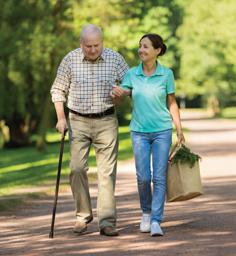 Senior man walking home with a staff member from grabbing some groceries