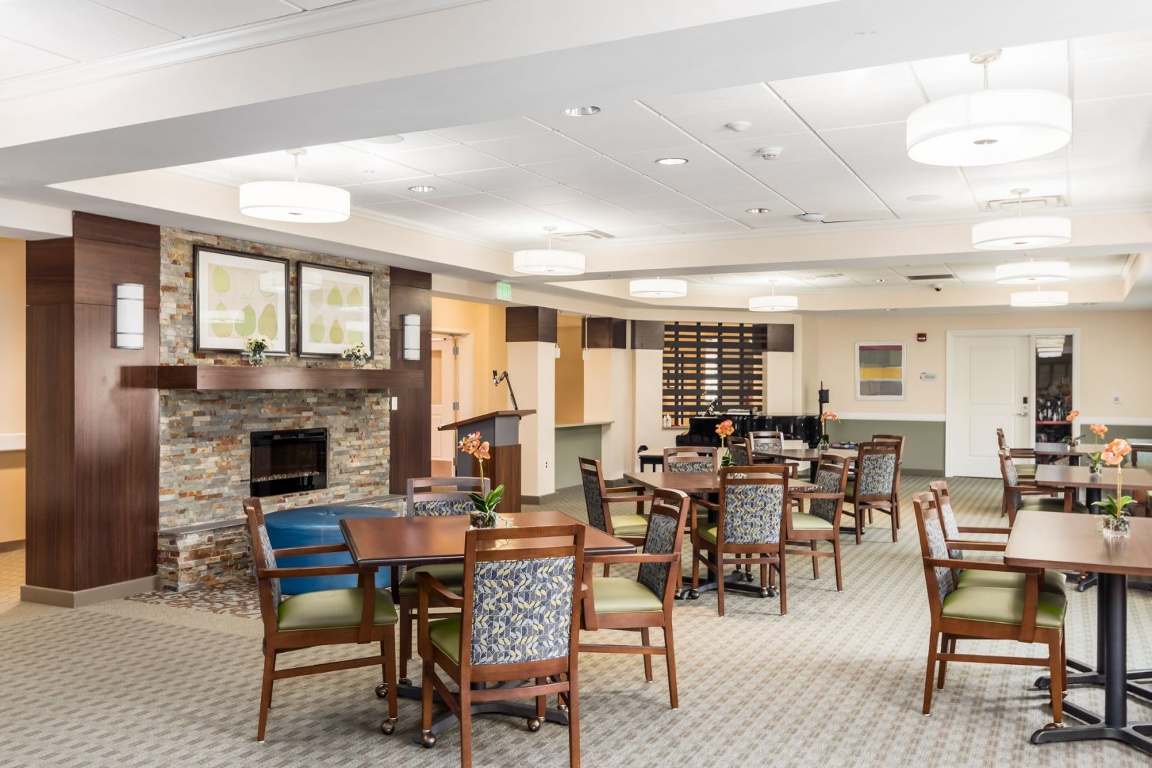 Common Area in Senior Living Community Common area with tables and chairs, a fireplace, and a piano in a senior living community.