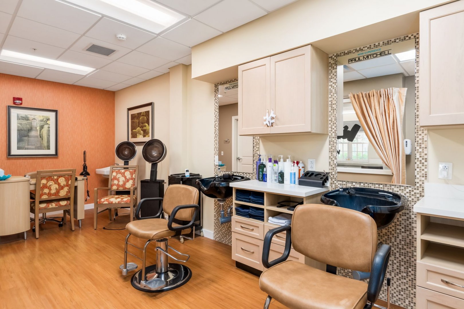 Salon in Senior Living Community Well-lit salon with hair dryers, styling chairs, mirrors, and hair products in a living community.