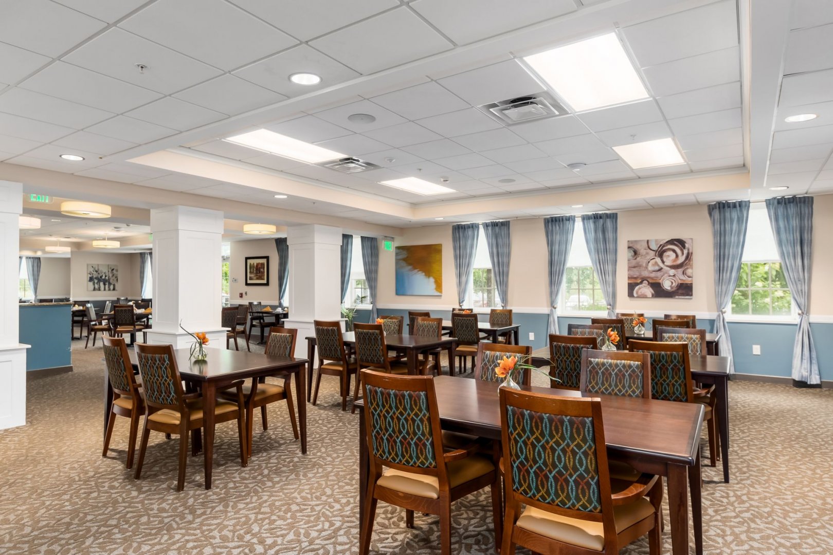 Senior Living Community Dining Area Dining area in a senior living community with tables, chairs, and large windows.