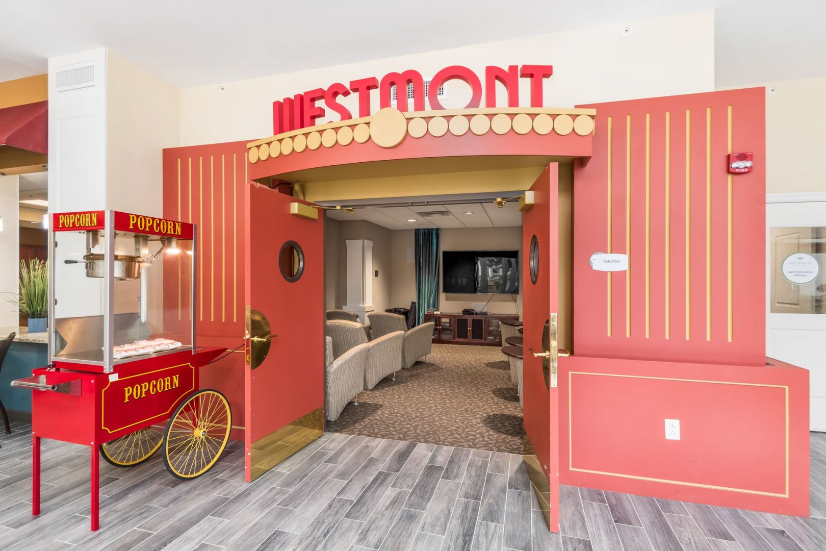 Westmont Theater Room Entrance Entrance to Westmont theater room with red doors and a popcorn cart in a senior living community.